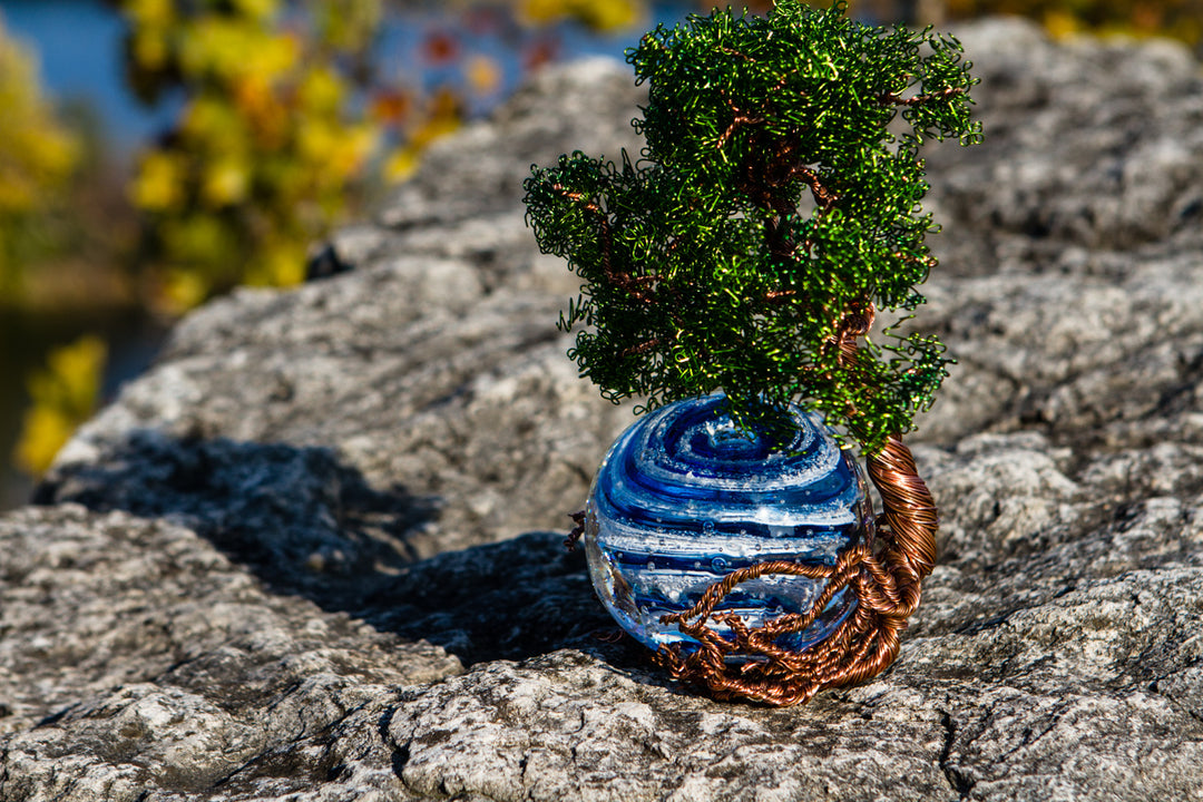 Ponderosa Tree of Life with blue Bubble Twist Orb perched on a rocky outcrop with a colorful blurred background