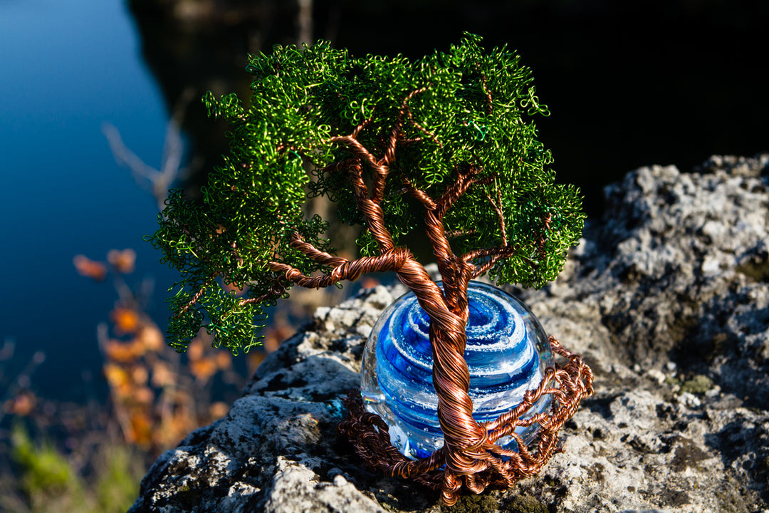 Close-up of Ponderosa Tree of Life and blue Bubble Twist Orb with copper wire trunk and a lake behind