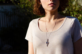 Photograph depicts model wearing the angel wing heart pendant on a chain around her neck. Silver necklace for cremation ash, silver remembrance jewelry, angel necklace for ash, silver angel necklace