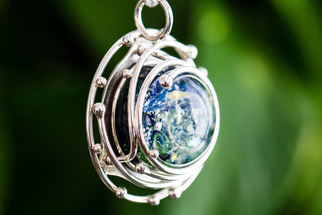 Caged Glass Ocean Pendant with a blue green ocean scene inside a silver wire cage and ash infusion
