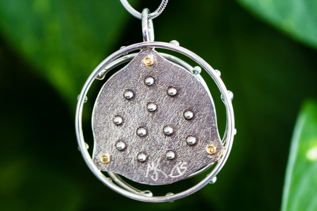 Caged Glass Ocean Pendant shown from the side, exposing the glass cabochon within a decorative silver cage