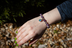 Photo depicts the Amethyst Healing Bracelet on the model's writst with dainty circle charm facing up. The dainty circle charm is made with light blue and turquoise opal. Amethyst bracelet, natural amethyst, amethyst stone, amethyst crystal bracelet, bracelet for ash, remembrance jewelry, bracelet for cremation ash