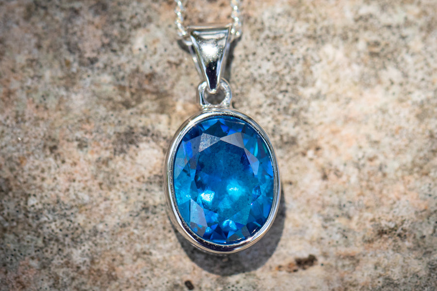 Crystal drop memorial pendant with a blue crystal in a silver setting on a chain