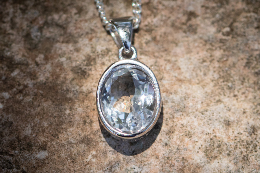 Blue crystal drop memorial pendant with silver setting on a chain designed to hold cremation ash.