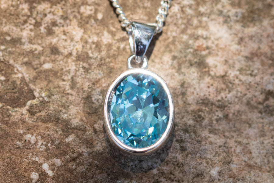 Crystal drop memorial pendant with teal blue crystal in a silver setting on a chain