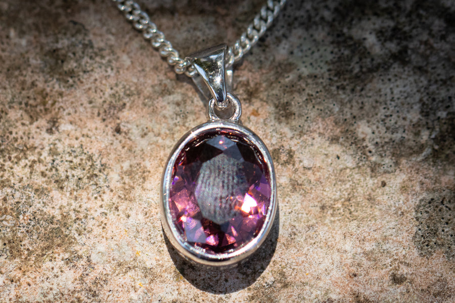 Purple oval crystal memorial pendant in a silver bezel on a chain