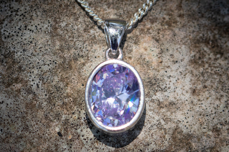 Crystal drop memorial pendant with a purple crystal in a silver setting on a chain