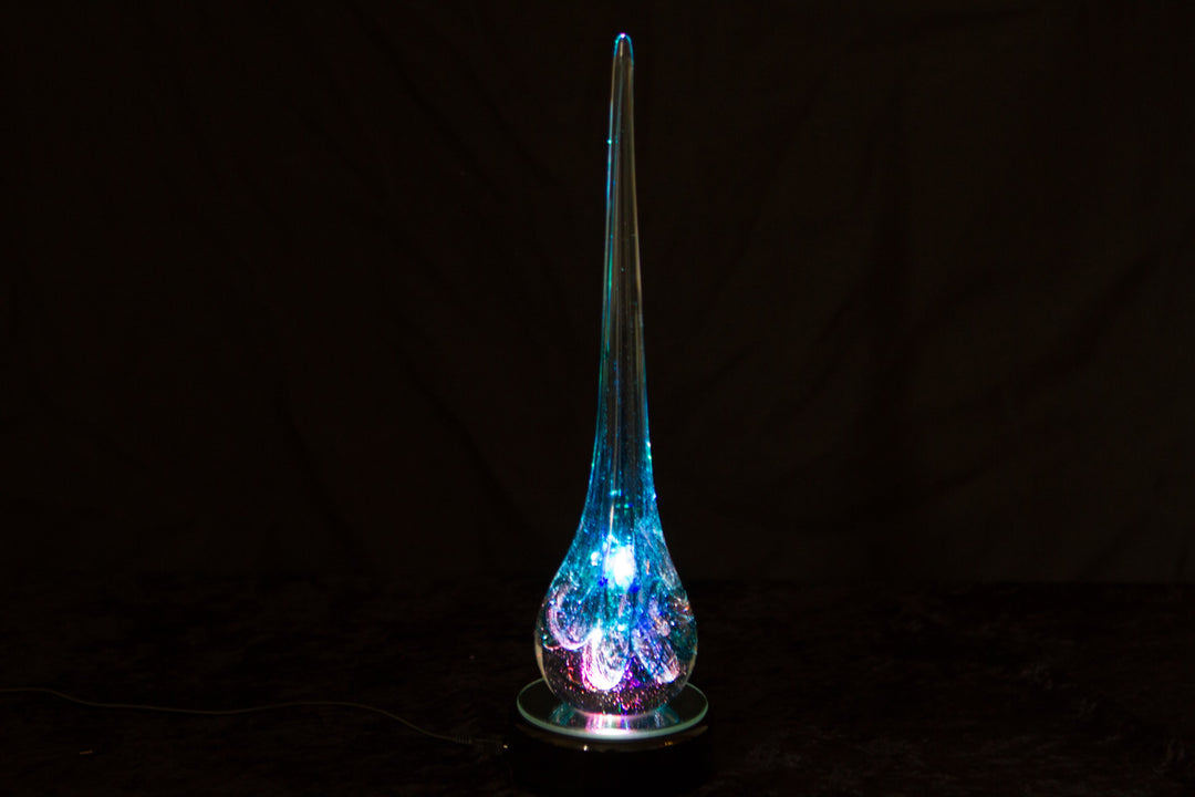 Curly blue glass angel drop with cremation ash on a dark display base