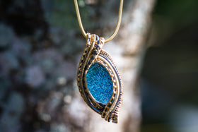 wirewrapped cremation jewelry with dichroic blue  glass hanging outside