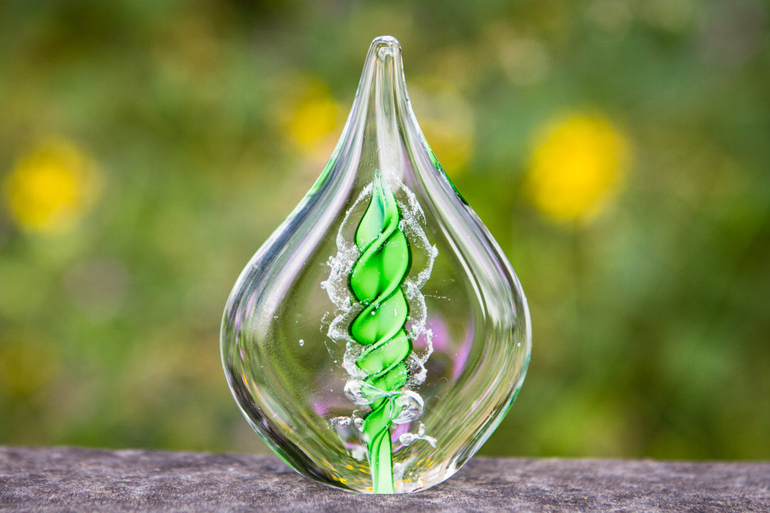 Clear glass memorial flame with a green spiral inside encasing cremation ashes