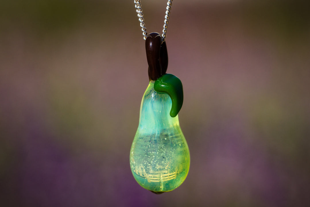 Glass pear pendant infused with cremation ash, translucent green pear with a brown top and green stem on a silver chain.