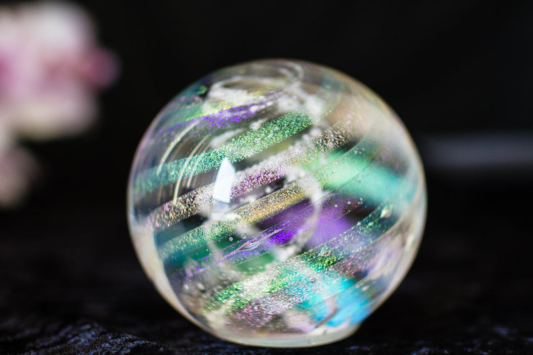 Dichroic rainbow glass orb containing cremation ash with iridescent color bands