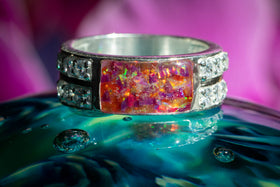 Photo depicts the Bedazzled Gemmmed Square Opal Ring on a glass surface. The sterling silver and zircon encrusted ring has a orange and magenta crushed opal stone. Sterling Silver Men's Ring, Sterling Silver Ring for Ash, Sterling Silver and Zircon Ring, Silver Remembrance Ring, Ring for Ash, Sterling Silver Remembrance Jewelry