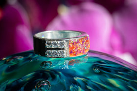 Photo depicts the side profile of the Bedazzled Gemmmed Square Opal Ring on a glass surface. The sterling silver and zircon encrusted ring has a orange and magenta crushed opal stone. Sterling Silver Men's Ring, Sterling Silver Ring for Ash, Sterling Silver and Zircon Ring, Silver Remembrance Ring, Ring for Ash, Sterling Silver Remembrance Jewelry