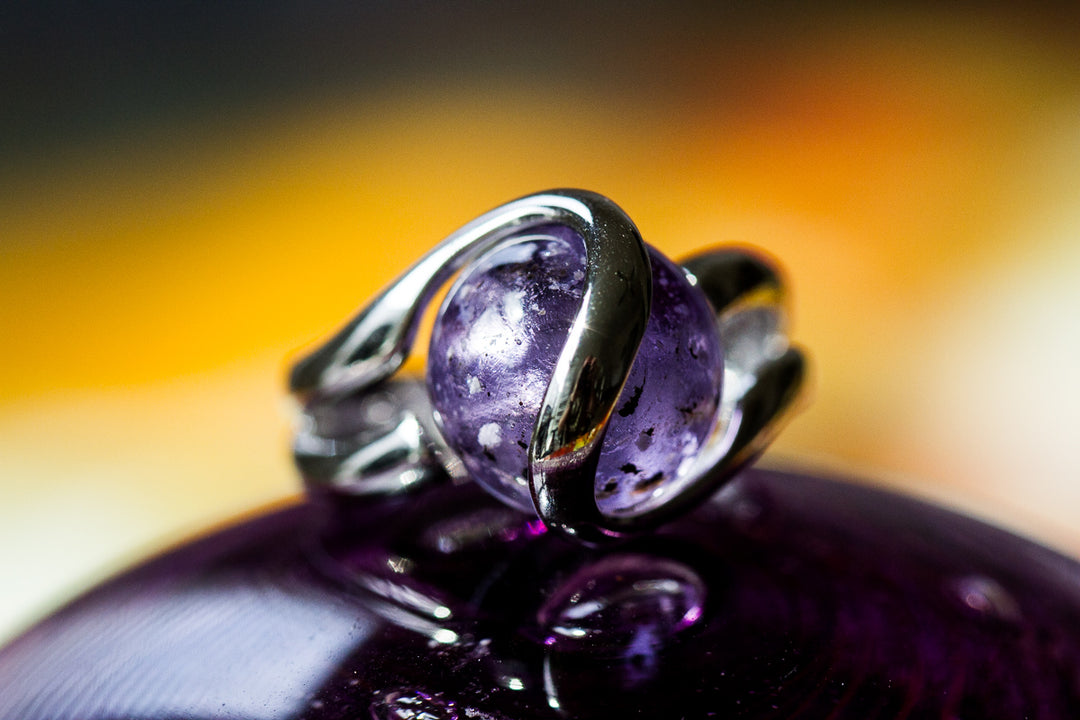 Close-up of a sterling silver ring featuring a purple 12mm glass marble infused with cremation ash.