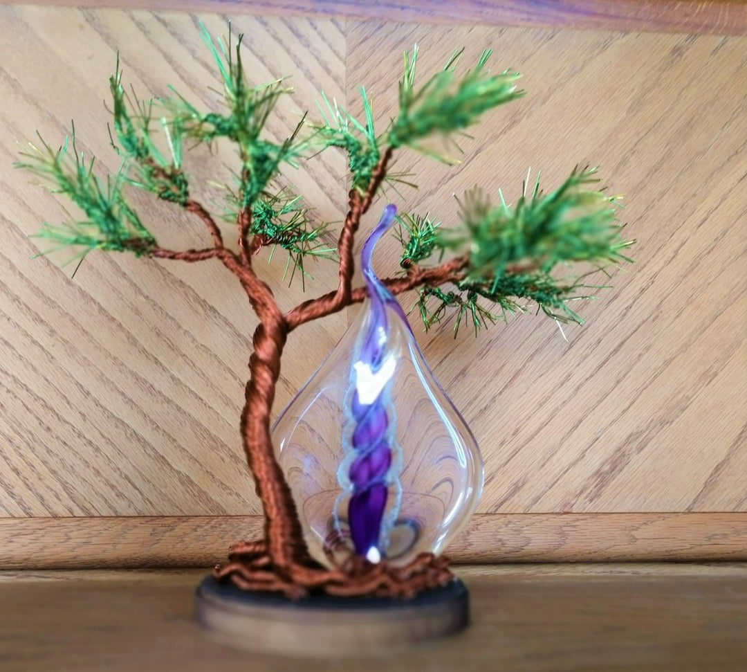 Close up of copper wire tree with a purple and blue glass memorial flame centerpiece in a teardrop glass ornament.