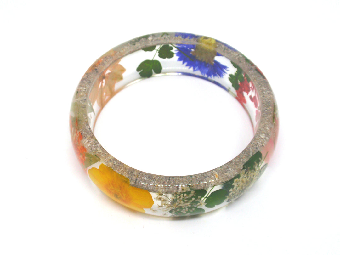 Curved resin bracelet filled with dried wildflowers and cremation ash for a personal keepsake