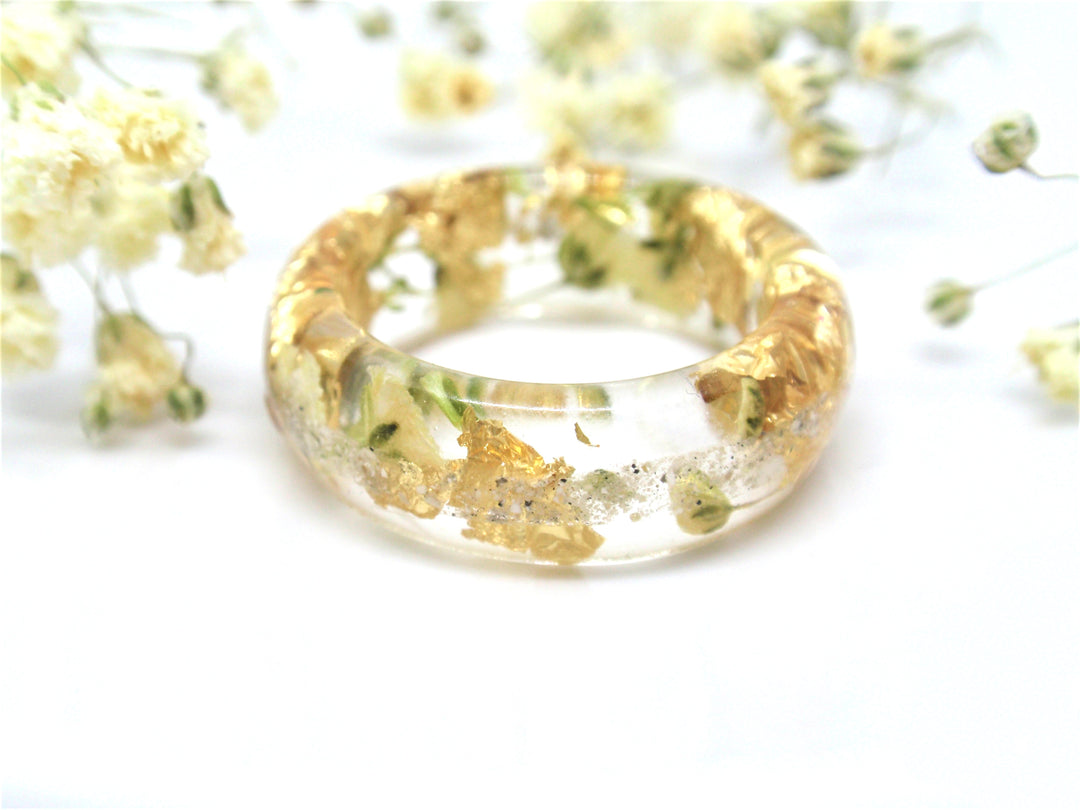 Clear resin ring holding real yellow flowers and gold flakes infused with cremains.