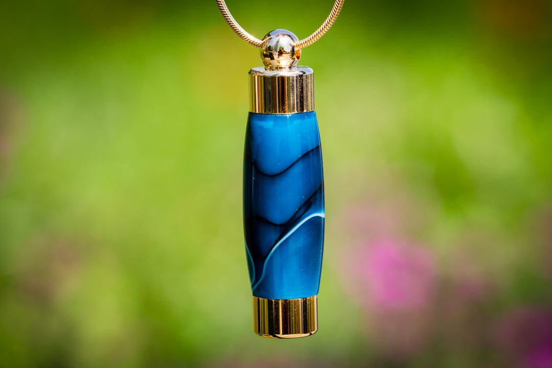Sapphire blue acrylic keepsake urn pendant with gold end caps on a gold chain.