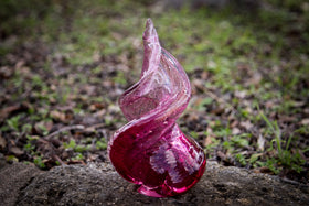 spiral glass with cremation ash in red outdoors.