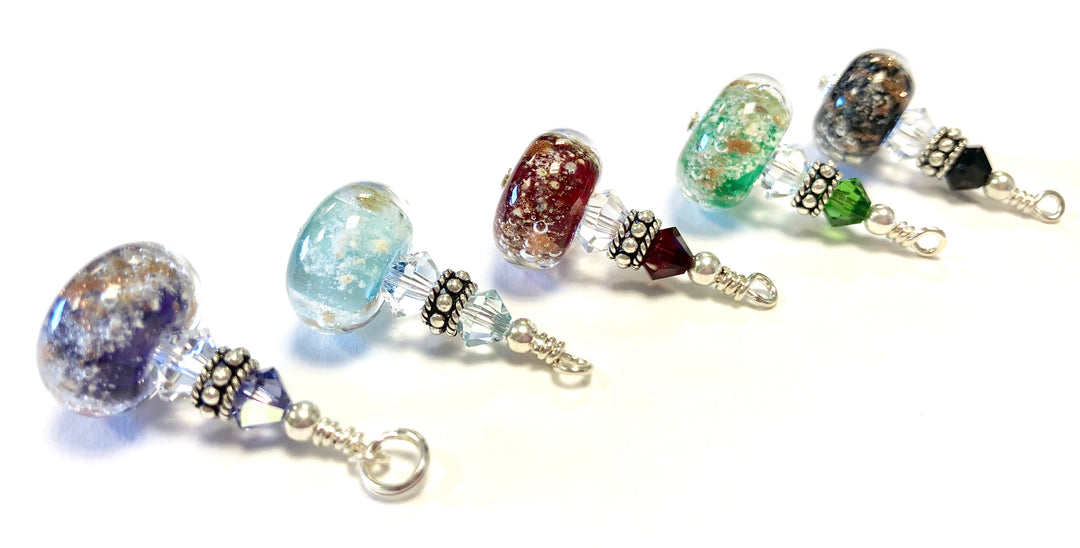 Colorful glass beads infused with cremains, separated by crystal spacers and silver end caps on a necklace segment.