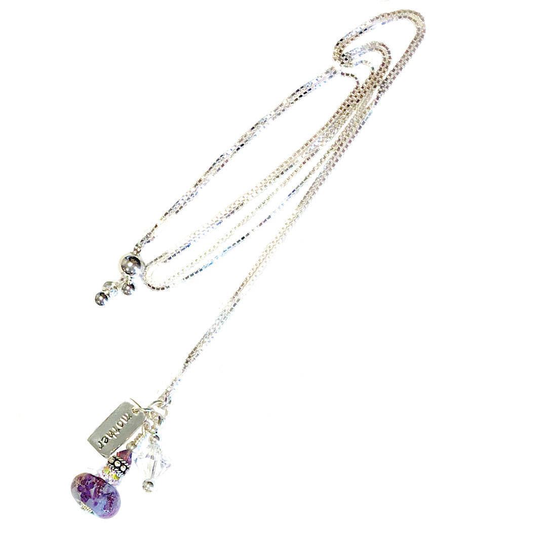 Multi strand silver necklace with a purple glass bead pendant and a mom tag among crystal accents