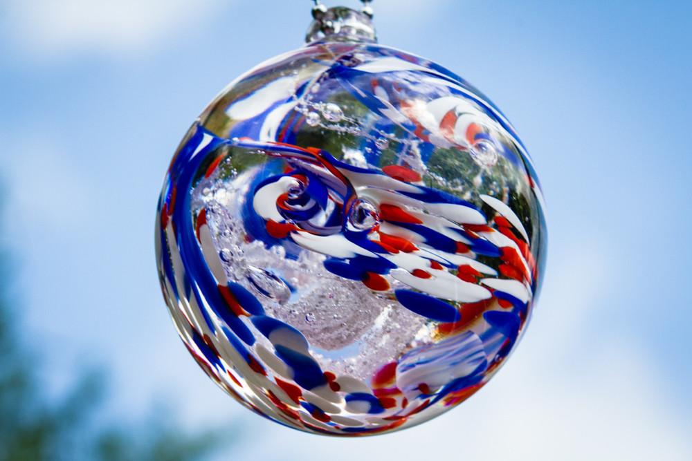 American confetti glass orb with red white and blue swirls and ashes inside.