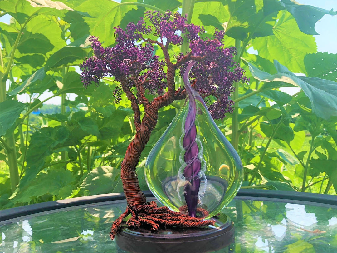 Copper wire Tree of Life with purple spiral memorial flame in a glass teardrop vase.