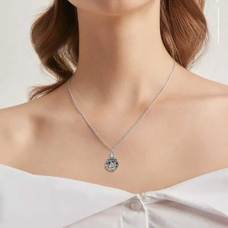 Silver chain necklace with a spherical filigree pendant encasing a crystal