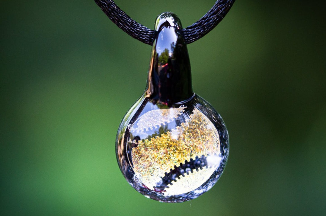 Glass pendant infused with cremation ash featuring a gold holographic baseball inside on an adjustable cord.