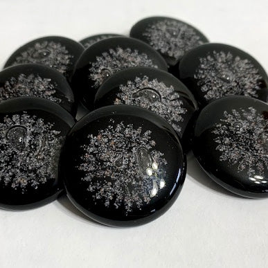 Set of black glass sharing stones with white snowflake patterns shown in a loose pile