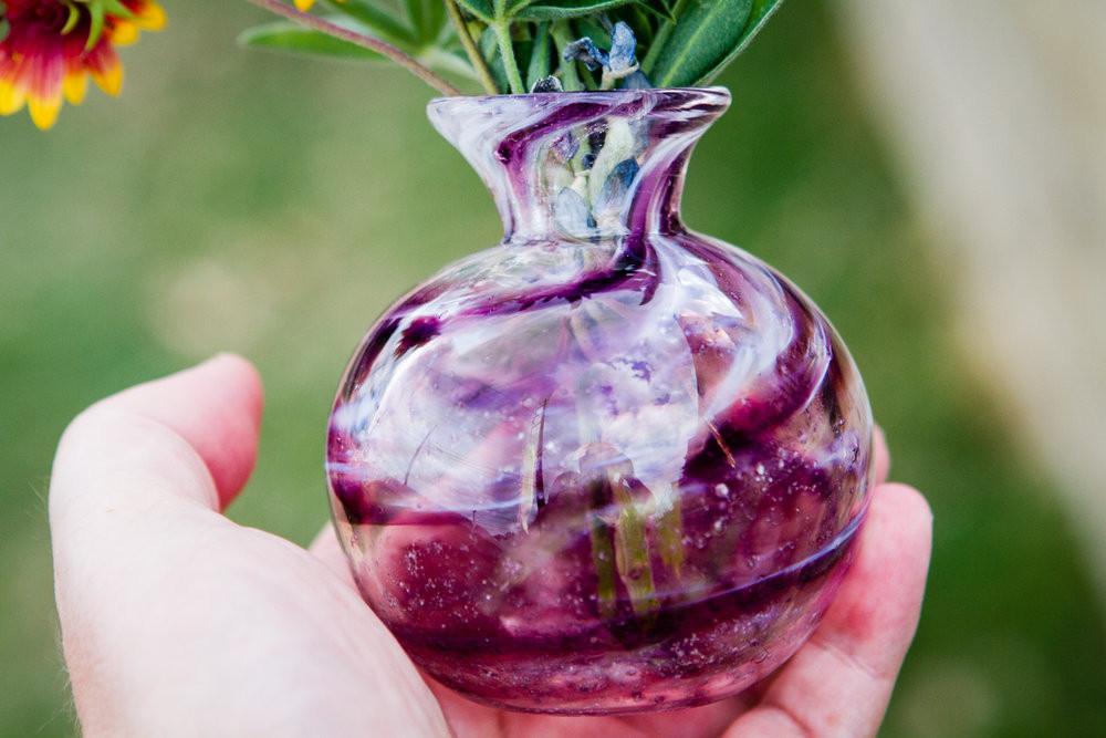 Purple marbled spherical bud vase with slender neck and visible cremation ashes ribbons inside