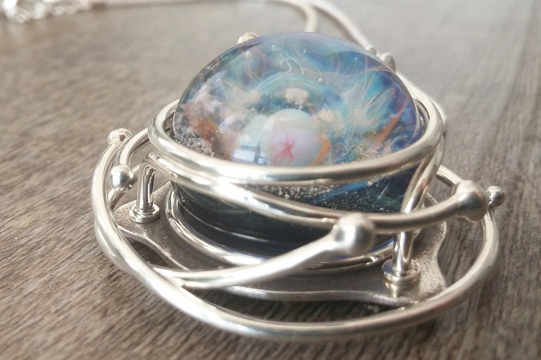 Close up of the galaxy pendant showing the glass cabochon inside the silver cage.