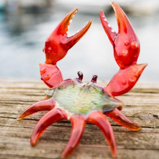Red memorial crab figurine with cremains concentrated in the shell on a wooden surface