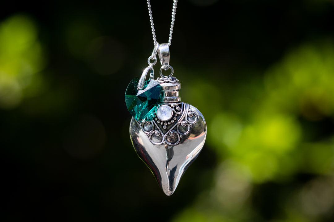 Sterling silver heart keepsake pendant with a teal birthstone crystal on a delicate silver chain.