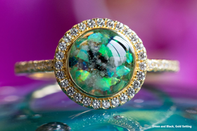 Photo depicts our Bedazzled Circle Opal Cremation Ring, in the colors green and black, sitting on a glass surface. Sterling Silver Ring, Sterling Silver Ring for Ash, Ring for Cremation Ash, Sterling Silver Remembrance Jewelry, Sterling Silver and Cubic Zirconia Ring