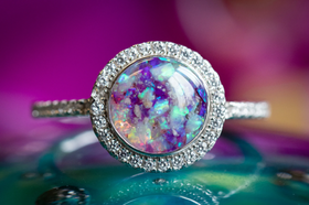 Photo depicts our Bedazzled Circle Opal Cremation Ring, in the colors purple and icy blue, sitting on a glass surface. Sterling Silver Ring, Sterling Silver Ring for Ash, Ring for Cremation Ash, Sterling Silver Remembrance Jewelry, Sterling Silver and Cubic Zirconia Ring
