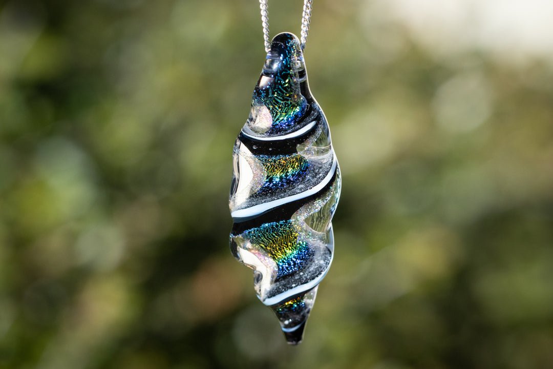 Dichroic ripple pendant with infused cremation ashes and iridescent blue green swirls on a silver chain