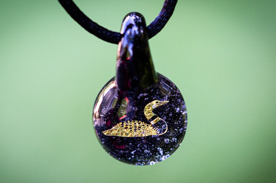 Loon hologram glass pendant with cremation ash and a gold loon silhouette on a black cord
