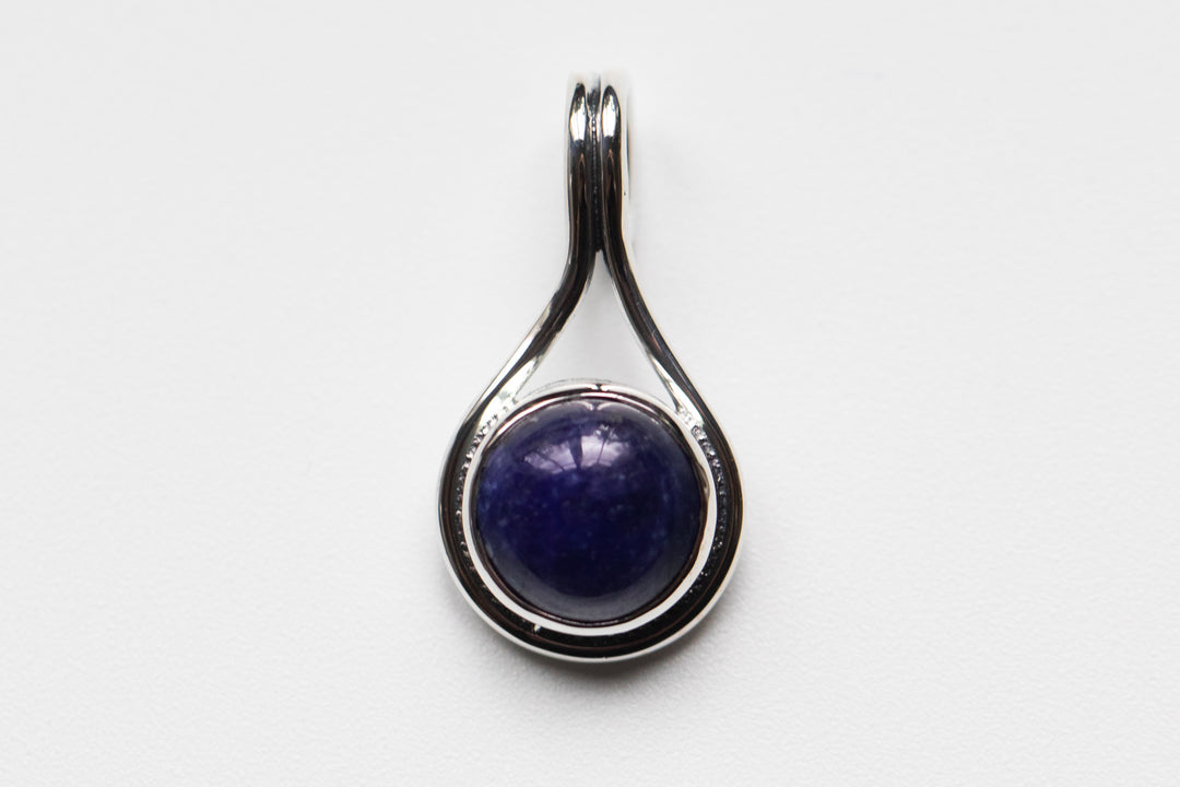 Stone Swirl Drop pendant in sterling silver with a round deep blue cabochon set in a curved teardrop frame