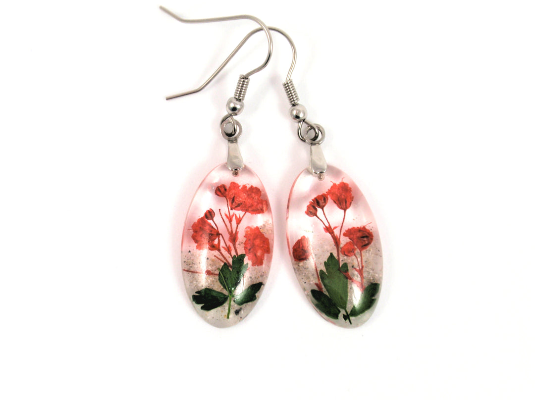 Oval clear resin earrings containing red baby's breath and green leaves with silver ear wires