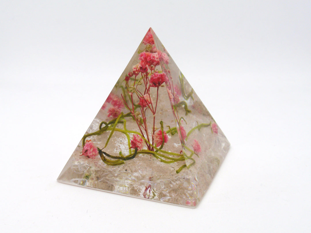 Clear pyramid memorial paperweight encasing pink dried flowers.