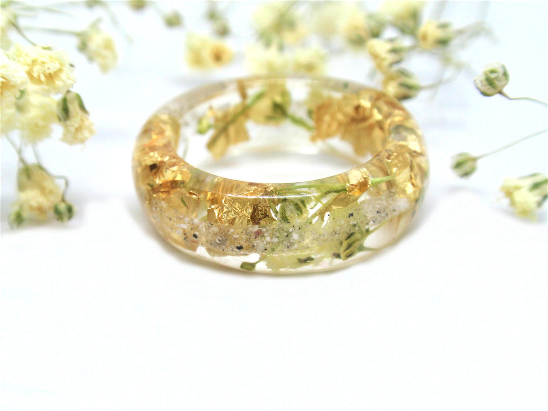 Crystal resin ring holding real yellow flower blooms and gold flakes with cremains