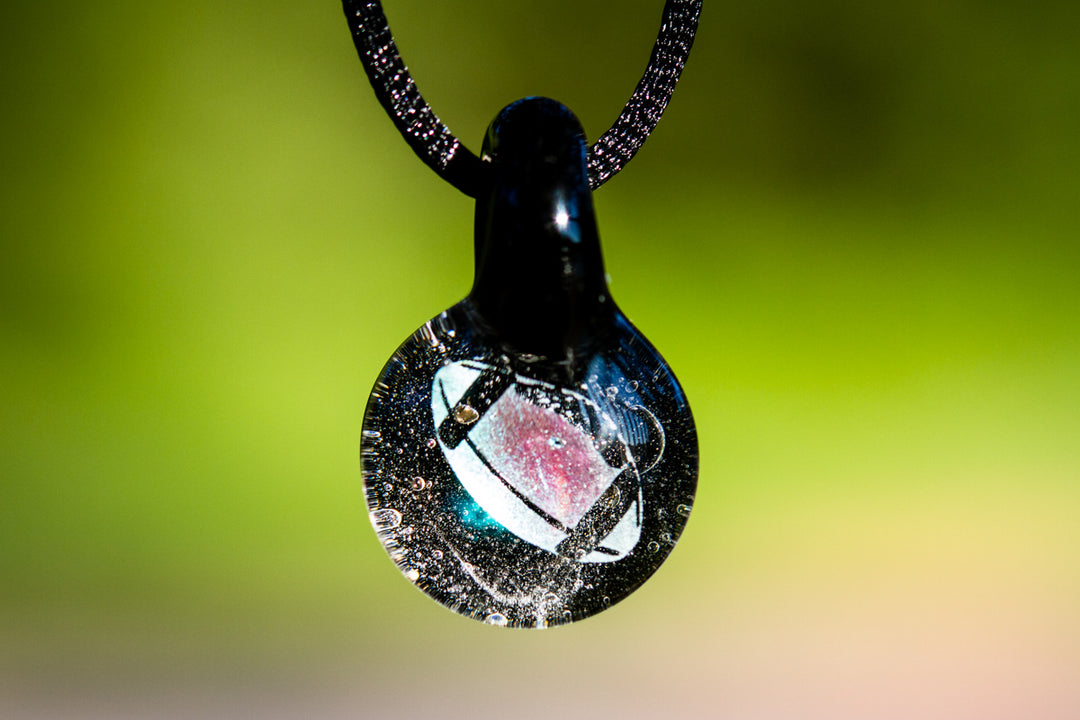 Football hologram pendant infused with cremation ash, a glass charm suspended from a black cord.
