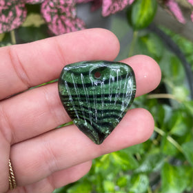 guitar pick with cremation ash forest green in hand