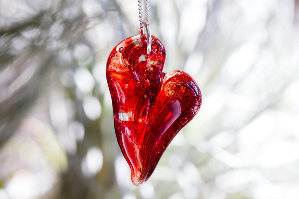 Red glass heart cremation pendant on a silver chain with ashes infused inside