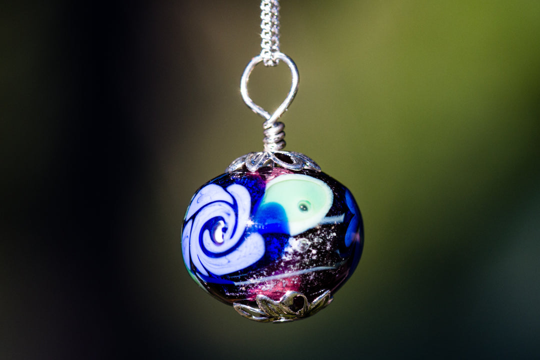 Glass flower pendant infused with cremation ash purple base with blue flower on a silver chain
