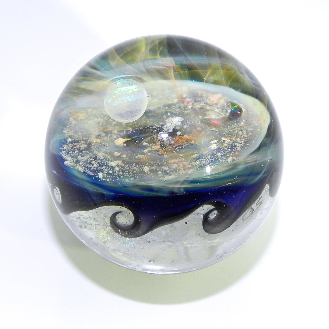 Wave Galaxy glass marble infused with cremation ash featuring blue and silver swirls and a tiny inner orb.