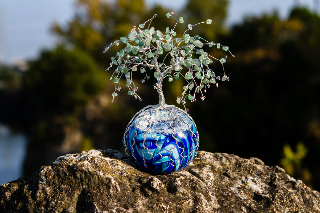 Wire wrapped tree of life with aventurine bead leaves atop a blue glass orb.