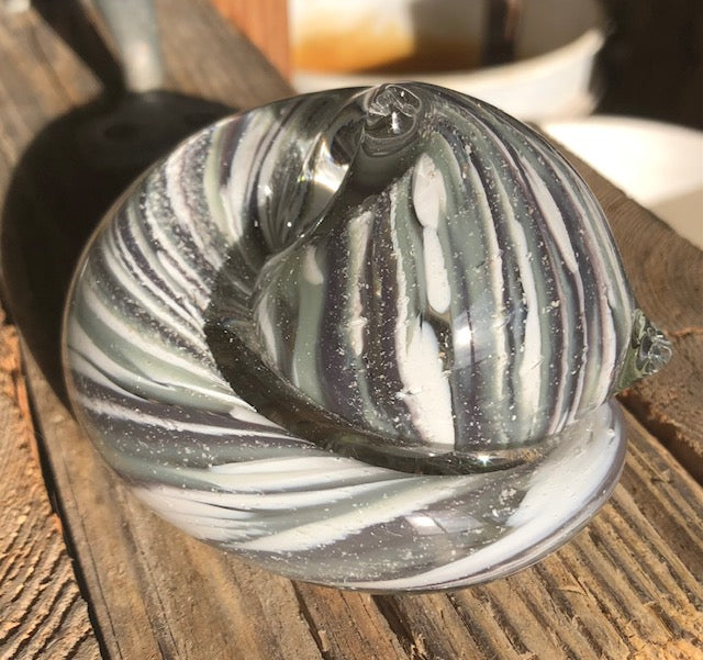 Close up of a memorial glass cat paperweight with swirled black white gray glass.
